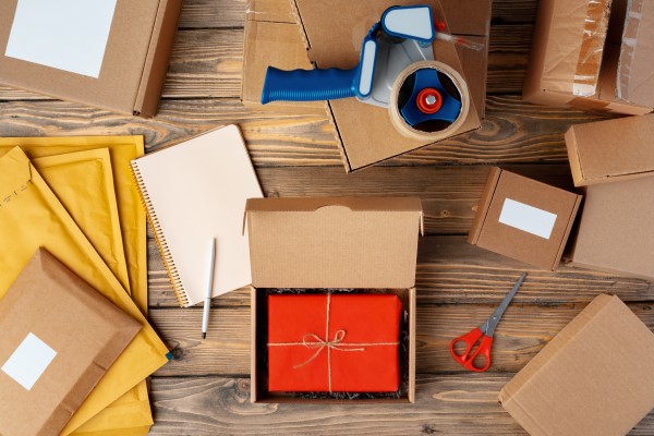 top-down view of essential packaging supplies, including boxes, padded envelopes, tape and scissors, preparing Christmas orders.